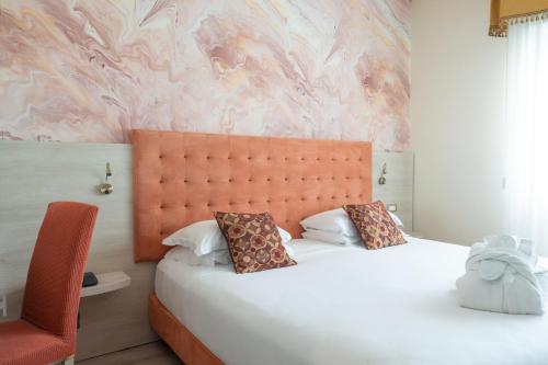 a bedroom with a large bed and a pink wall at Hotel Castello Artemide Congressi in Castel San Pietro Terme