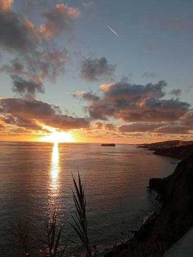 a sunset over a body of water with the sun setting at Casa Dona Rosa in Ponta Delgada