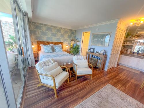 a bedroom with a bed and two chairs at Honu Hideaway Studio at Royal Garden in Honolulu