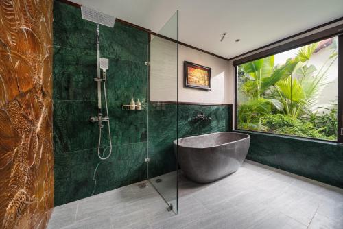a bathroom with a tub and a glass shower at The Greenary Garden in Xuân Sơn