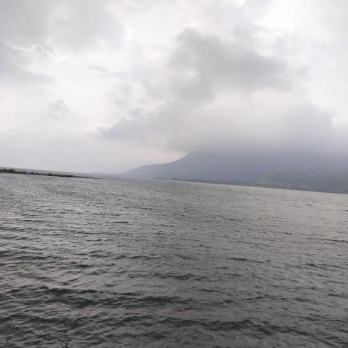 a large body of water under a cloudy sky at Camping blue sky heaven malshej in Malshej Ghat