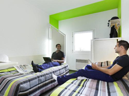 two men sitting on beds in a room with their laptops at hotelF1 Lyon Gerland Vénissieux in Vénissieux