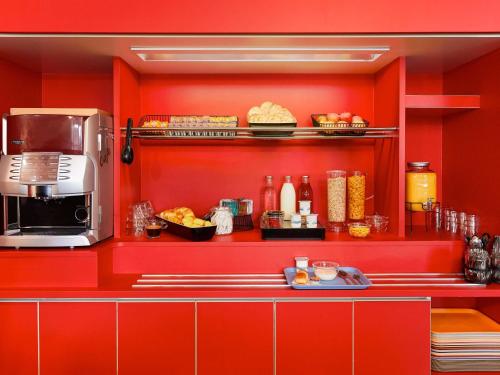 a kitchen with red walls and a counter with food at hotelF1 Lyon Gerland Vénissieux in Vénissieux