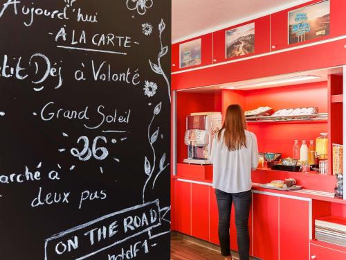 a woman standing in front of a counter in a kitchen at hotelF1 Lyon Gerland Vénissieux in Vénissieux