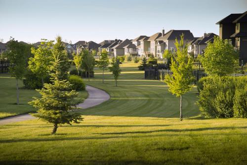 a golf course with trees and houses in the background at Comfy Home in Harbour Landing - Regina in Regina