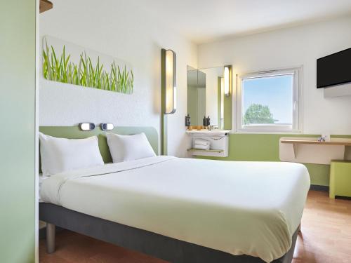a large white bed in a room with a window at ibis budget Santeny in Santeny