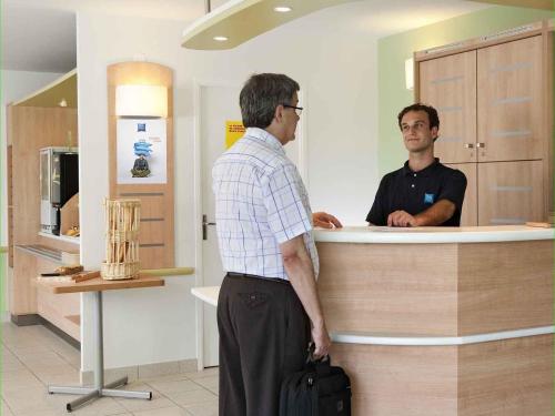 two men standing at a counter in a kitchen at ibis budget Santeny in Santeny