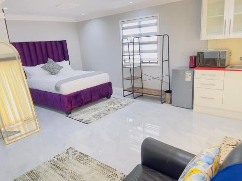 Una sala de estar con una cama y una cocina. en The Airport Terminal Guesthouse, en Kempton Park