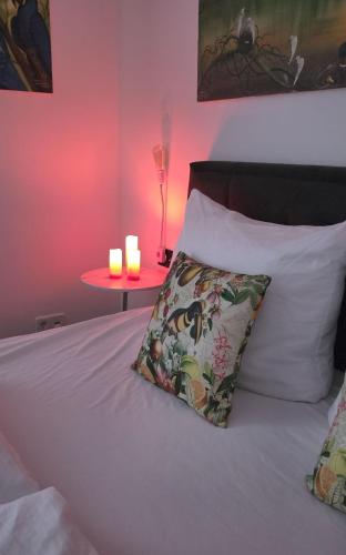a bed with a pillow and two candles on a table at Exotic Tropical Palace - ComfyHome Apartments Stuttgart in Stuttgart