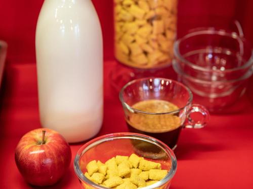 a table with a glass bowl of cereal and an apple and milk at hotelF1 Villepinte Parc des Expositions in Villepinte