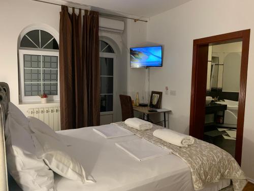 a bedroom with a white bed and a television at Diplomat Haven in Sremska Kamenica