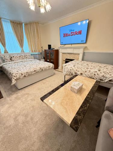 a room with two beds and a tv on the wall at The RS Inn Cozy Homestay Premium Private Rooms With Parking Near Birmingham Airport, Lake Park For Solo, Couples & Family in Kingshurst
