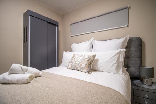 a bedroom with a large bed with white pillows at Waterfall Ridge Luxurious Apartments - Backup Power! in Midrand