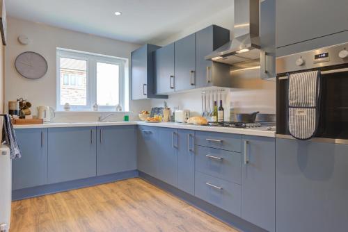 a large kitchen with blue cabinets and a window at Marriott House sleeps 5 in Bourne with parking in Bourne