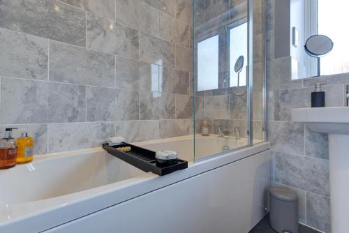 a bathroom with a tub and a sink at Marriott House in Bourne
