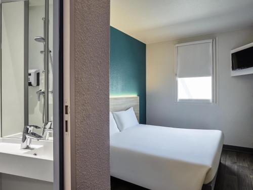 a hotel room with a white bed and a sink at hotelF1 Compiègne in Venette