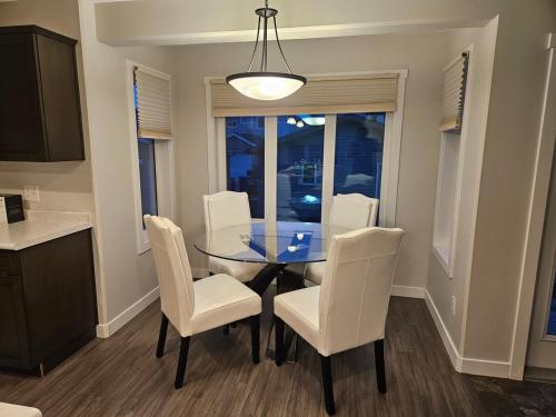 a dining room with a glass table and white chairs at Comfy Home in Harbour Landing - Regina in Regina