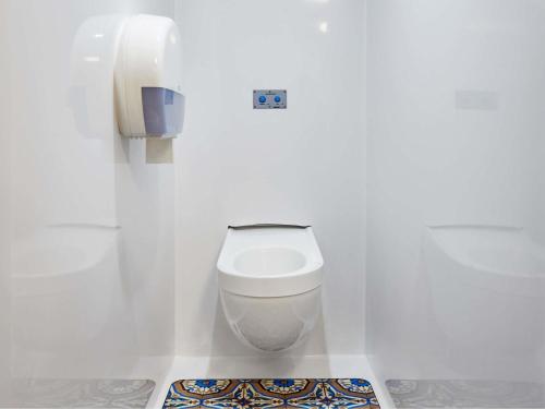 a white toilet in a white bathroom with a phone at hotelF1 Le Mans Nord in Saint-Saturnin