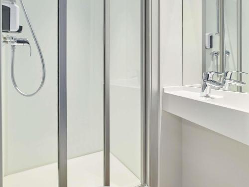 a shower with a glass door next to a sink at hotelF1 Chaumont in Chaumont