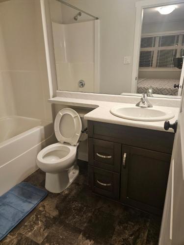 a bathroom with a toilet and a sink and a mirror at Comfy Home in Harbour Landing - Regina in Regina