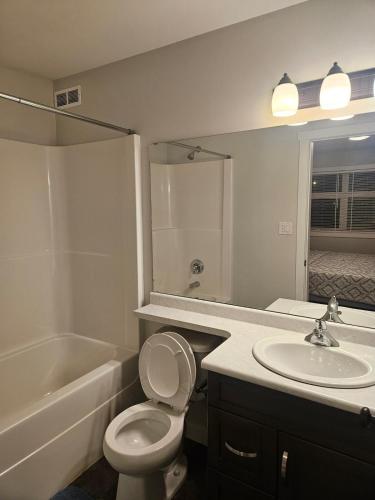 a bathroom with a toilet and a sink and a tub at Comfy Home in Harbour Landing - Regina in Regina