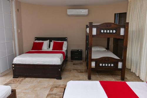 a bedroom with two bunk beds with red pillows at Hotel Campestre Villa Ocha in Valledupar