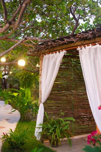 a bird house with white curtains in a garden at Casa Peroá Pousada in Icaraí