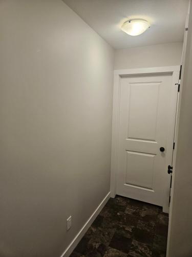 an empty room with a white door and a tile floor at Comfy Home in Harbour Landing - Regina in Regina