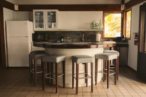 a kitchen with a bar with stools and a refrigerator at Oceania Villas in Culebra