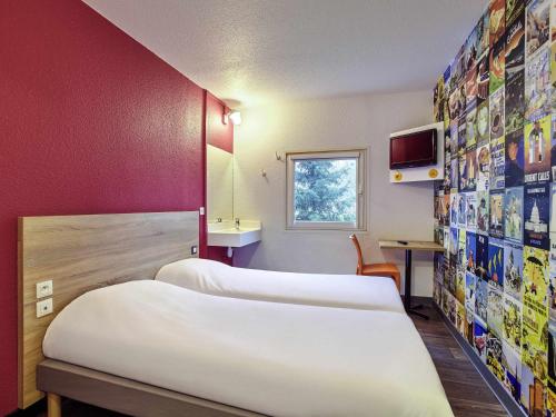 a hotel room with two beds and a tv at hotelF1 Calais Coquelles in Coquelles