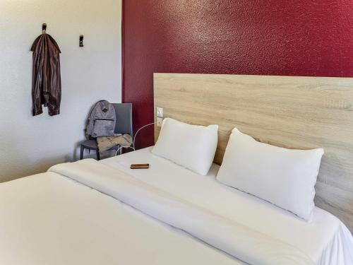 a bed with two pillows and a backpack in a room at hotelF1 Calais Coquelles in Coquelles