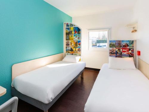 two beds in a room with a blue wall at hotelF1 Avranches Baie Du Mont Saint Michel in Saint-Quentin-sur-le-Homme