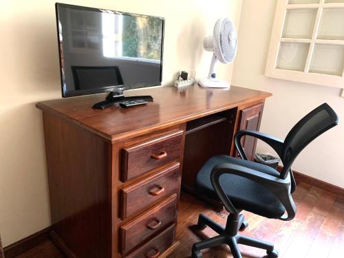 a desk with a television and a black chair at Pousada Reserva Gran Descanso in Embu