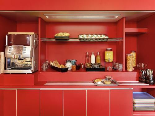a kitchen with red walls and a counter with food at hotelF1 Fréjus Roquebrune sur Argens in Roquebrune-sur-Argens