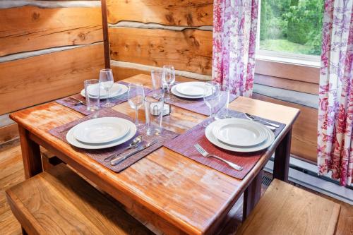 a wooden table with plates and wine glasses on it at Romantic Cabin Getaway - King Bed - Fast Wi-Fi - Pet-Friendly in Meadows of Dan