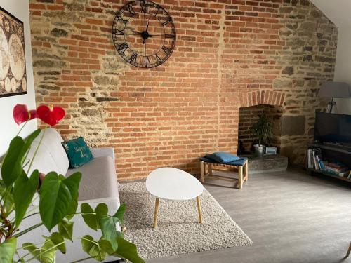 a living room with a brick wall with a clock at MOINES - Centre historique de charme in Vannes