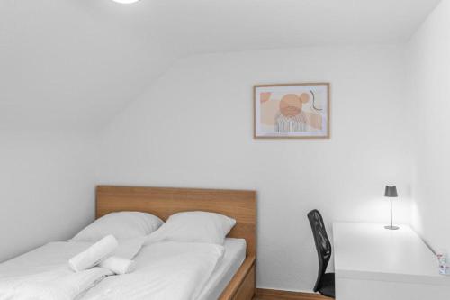 a bedroom with a bed with white sheets and a desk at Walnut Tree Apart in Bergisch Gladbach