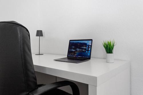 a laptop computer sitting on top of a white desk at Walnut Tree Apart in Bergisch Gladbach