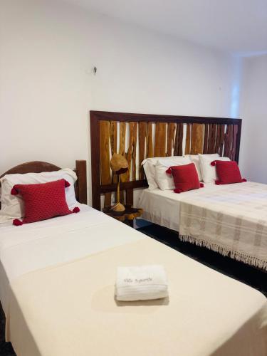 two beds with red and white pillows in a room at Villa Jaguaribe in Fortim