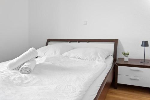 a white bed with white sheets and pillows and a nightstand at Walnut Tree Apart in Bergisch Gladbach