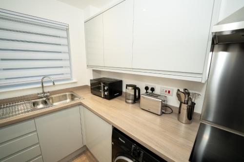 a kitchen with white cabinets and a counter top at Chapel Waters Sleeps 6 with Private Parking in Lower Bradway