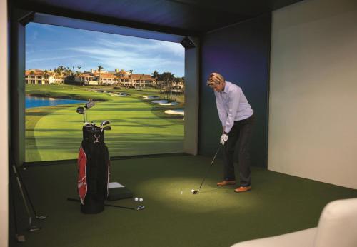 a man playing golf in a room with a large window at EUROPÄISCHER HOF Bad Gastein in Bad Gastein