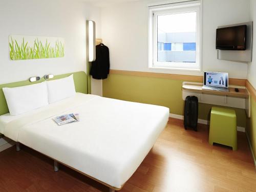 a bedroom with a large white bed and a window at ibis budget L'Isle Adam in LʼIsle-Adam