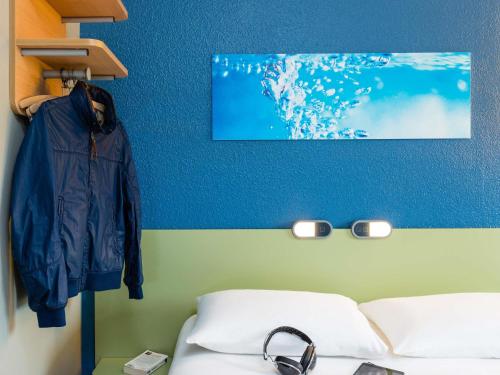 a room with a bed and a jacket hanging on a wall at Ibis Budget Angers Parc des Expositions in Saint-Sylvain-dʼAnjou