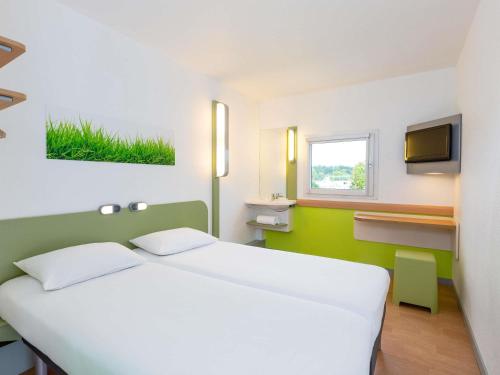 a bedroom with a large white bed and a tv at Ibis Budget Angers Parc des Expositions in Saint-Sylvain-dʼAnjou