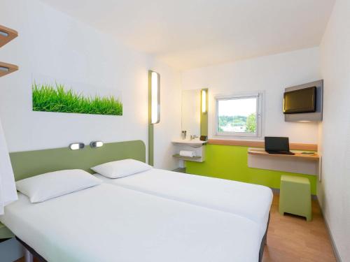 a bedroom with a large white bed and a television at Ibis Budget Angers Parc des Expositions in Saint-Sylvain-dʼAnjou
