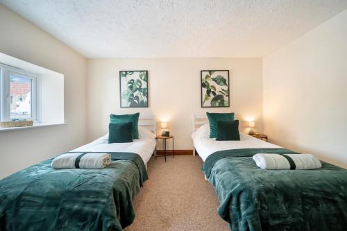 two beds in a room with green sheets at 4 Bdr House with TV, Wifi, near Thetford town in Thetford