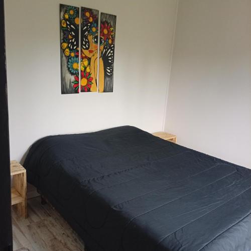 a bedroom with a blue bed and a painting on the wall at El Refugio Tapalque in Tapalqué