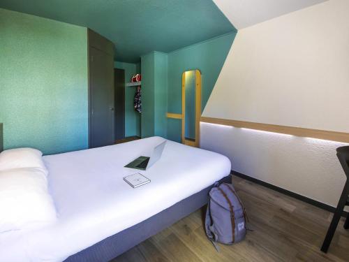 a room with a bed with a book on it at ibis budget Grenoble Voreppe in Voreppe