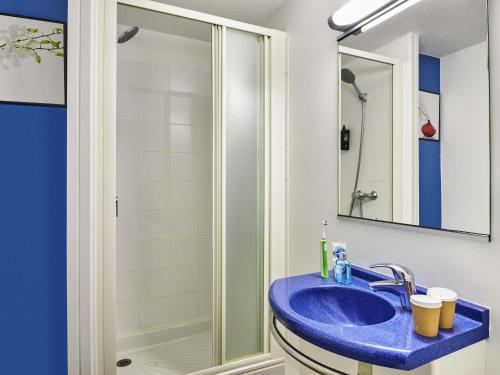 a bathroom with a blue sink and a shower at Ibis Budget Versailles Coignieres in Coignières